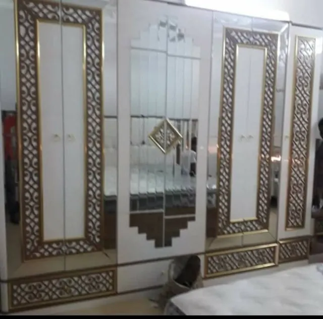 دولاب فاتح اللون بأبواب ذات زخارف ومرايا وسطية.